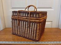 Front view of rectangular two-tone wicker picnic basket with handle and ruler for scale