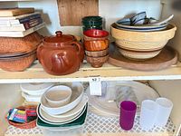 Overall view of shelves with ceramic pot, wooden bowls, plastic containers, dishes