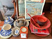 Group shot of entire lot including blue & white ceramics, cast iron teapot, red lacquerware, red tin, cookbooks, print