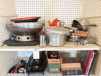 Overview of upper and lower shelves showing cookware, utensils, books, and gas stove