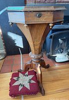 Closed sewing table on tripod base with footstool in foreground