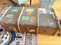 Full view of trunk front showing wooden slats, metal hardware, travel stickers