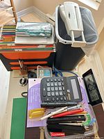 Top view of entire lot showing shredder, trays, calculator, clock, stapler, tape, pens, envelopes, notebook