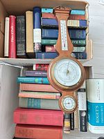 Front view of banjo barometer resting on boxes of books