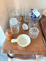 Group view of all items on table including glass vases, jar, creamer, bowl, dish, wooden container
