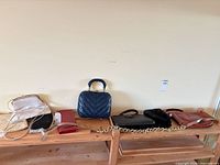 Overview of seven bags and chain strap on wooden shelf