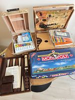 Overview showing artist paint case, second artist box, sketch books, Derwent tin, backgammon set, Monopoly box