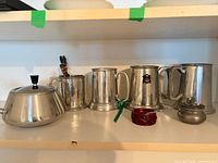 Shelf with four metal tankards, lidded pot, red dish, small pewter box