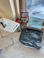 Lot overview showing bath stool, Omron monitor box, cane box, cushion, underpad