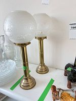 Pair of brass column lamps with frosted globes on tabletop