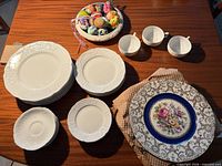 Stacked white Classic Rose dinner, salad, bread plates, saucers, cobalt floral plates and three white teacups on table