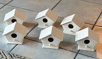 Group of six unglazed ceramic mini birdhouses on tile floor
