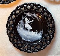 Front of black glass plate showing white enamel girl on swing scene and lace rim