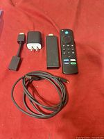 All components laid out: streaming stick, remote, power adapter, HDMI extender, USB cable