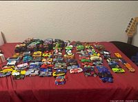 Wide shot of entire assortment of toy vehicles laid out on a red surface
