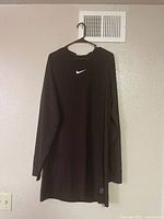 Full front view of black Nike long-sleeve top on hanger
