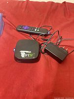 Roku 2 box, remote, power adapter on red surface