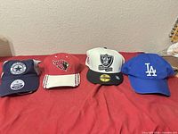 Four team caps lined up on red surface