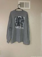 Front view of grey long-sleeve shirt on hanger showing full graphic and size
