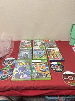 Overview of eight cased games and three loose discs on red surface