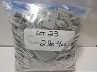 Front view of sealed bag filled with grey LEGO pieces, label shows lot and weight