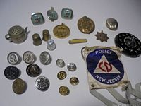 Overview of entire lot showing buttons, medals, armband, tea infuser, thimbles, cufflinks, tie clip, compact and lock dial
