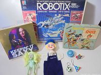 Overall lot showing Robotix box, Peter Pan quiz box, Kenny G game, Dutch Boy puppet, green action figure, yo-yo, keychain puzzles