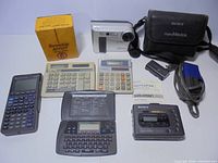 Group shot of Sony Digital Mavica camera with accessories, Sony Walkman, calculators, organizer, battery and charger