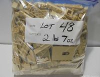 Sealed plastic bag filled with tan LEGO pieces labeled 2 lbs 7 oz