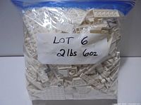 Sealed plastic bag filled with white LEGO pieces labeled 2 lb 6 oz