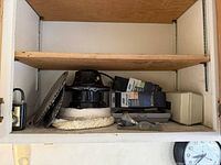 Overview of cabinet shelf with polisher, saw blade, ProSand boxes, block plane and cases