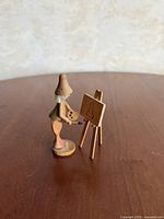 Painter figurine facing canvas on easel