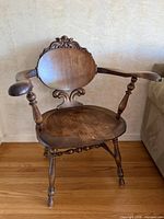 Front view showing carved crest, round back, arms, seat, turned legs