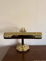 Front view of brass piano lamp on wood surface