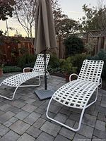 Pair of Brown Jordan white strap chaise lounges on patio