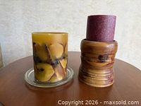 Side view of both candles; shows glass container, wooden holder