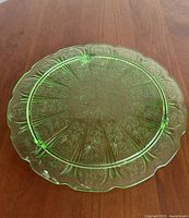 Top view of green depression glass platter showing scalloped edge and central floral motif