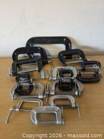 All eleven C-clamps arranged on tabletop showing size range and finishes