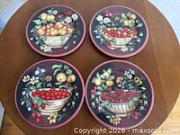 All four ceramic fruit motif plates on table