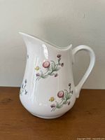 Left profile of white ceramic pitcher showing floral decoration