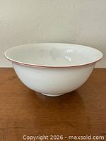 Side view of white ribbed porcelain bowl with red rim