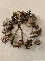 Front view of brass wreath showing all attached holiday figures and ribbon hanger