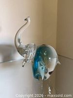 Profile view of clear and blue-green glass elephant showing trunk and coloration