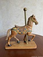 Full view of carousel horse on base with pole