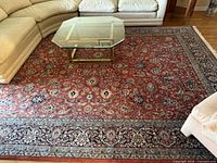 Full view of handmade Indian Kashan wool rug under coffee table and sectional