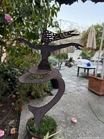 Front view of rusted metal mermaid hanging spiral