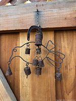 Full view of iron bird wind chime showing outline, bells, and horseshoe hanger