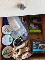 Open drawer showing tubs, bag of anchors, roofing nail box and loose screws