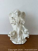 Front view of white porcelain angel figurine with cherubs