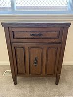 Front view of closed wood cabinet housing sewing machine